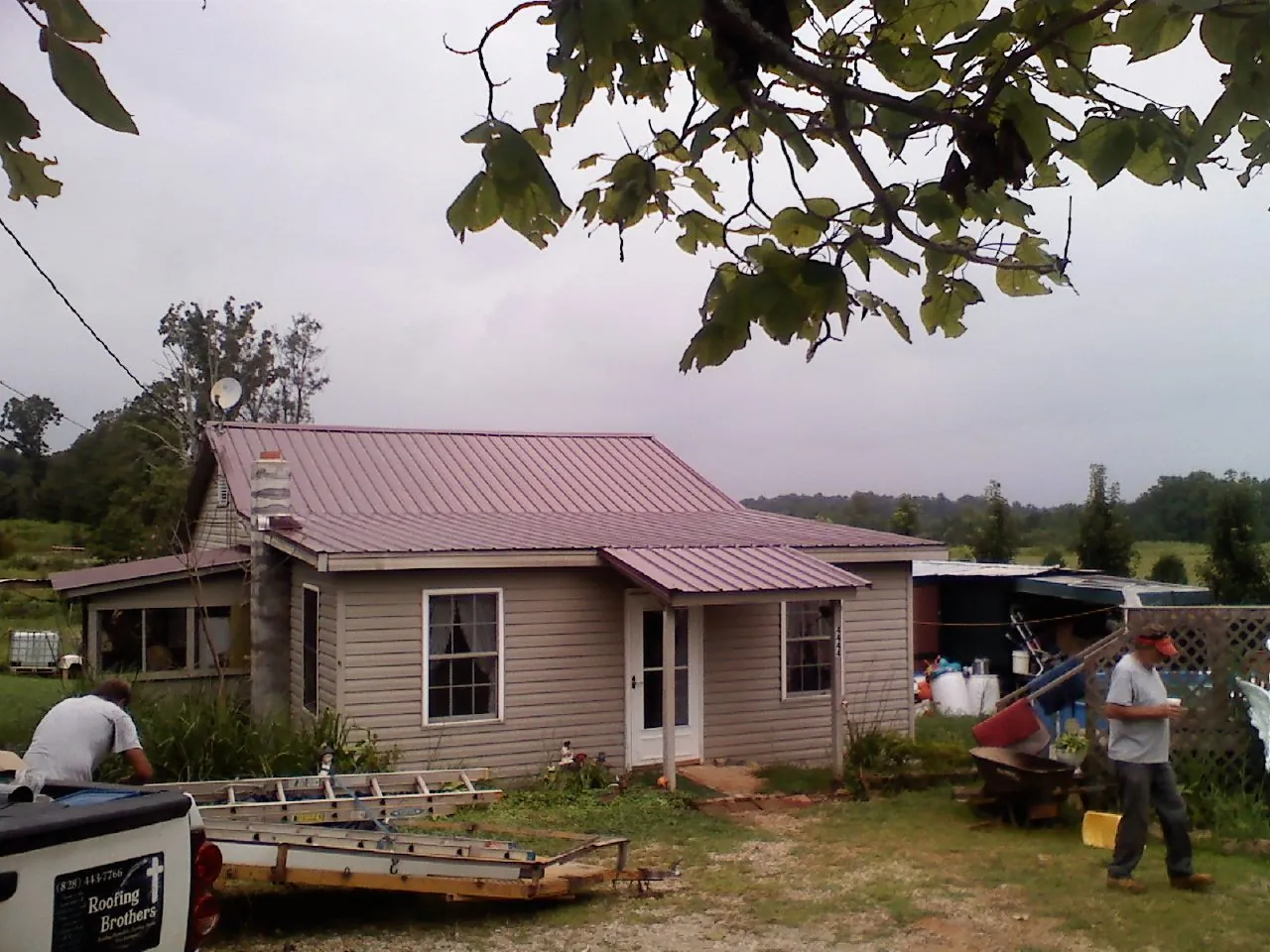 Crew finishing a mauve metal roof on a small farmhouse in West Harrison