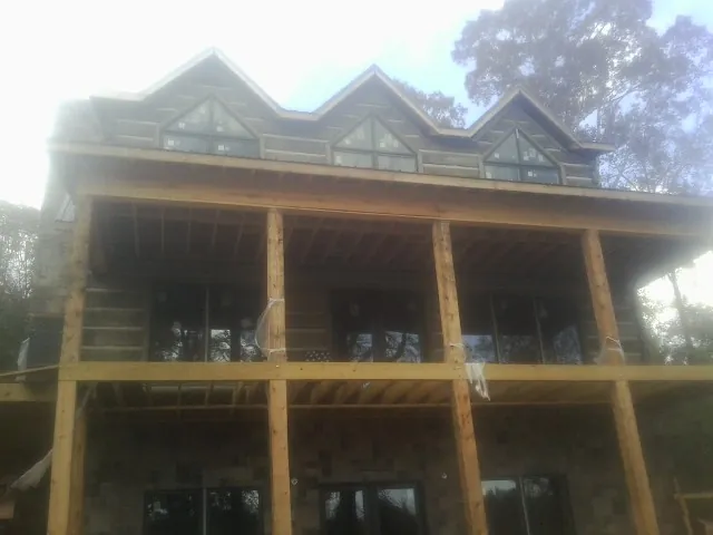 Dormers and porch framing on a large log home under construction — Roof Coating work by our crew in West Harrison