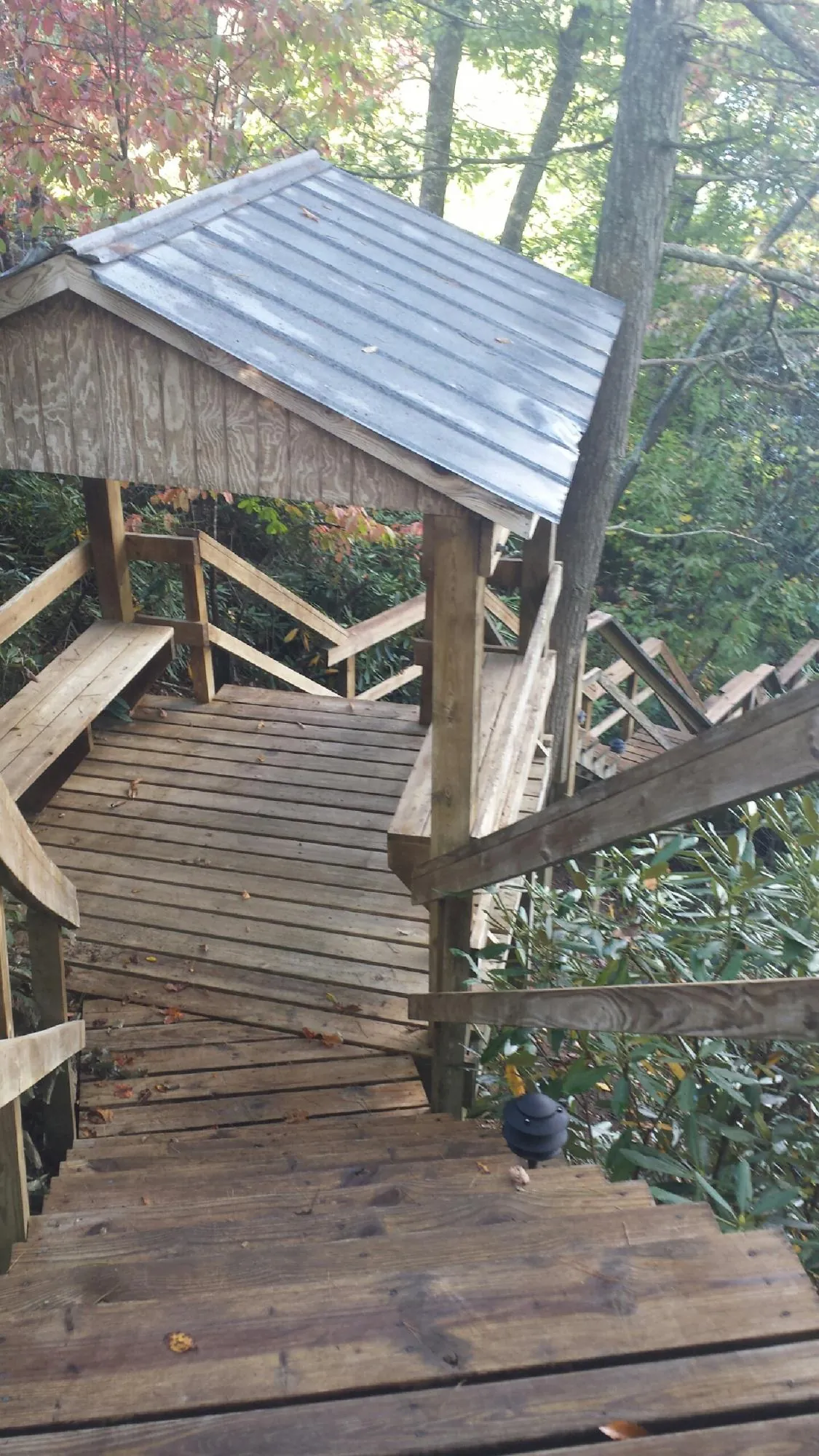 Metal roofed shelter over wooden steps on a wooded walkway — Skylight Repair & Installation work by our crew in West Harrison